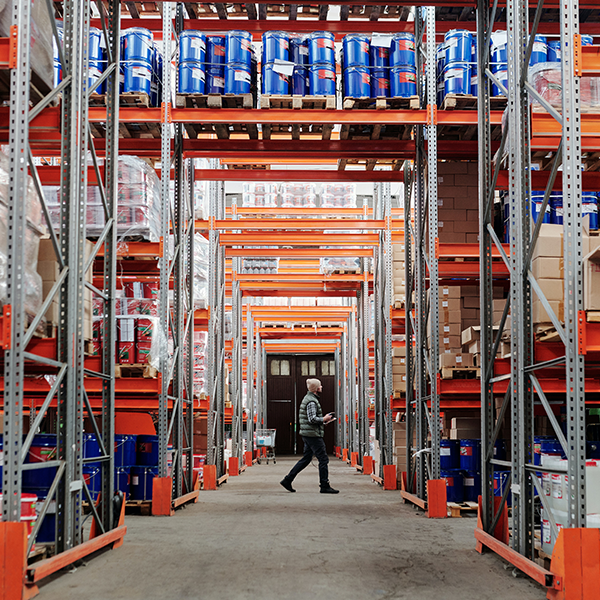 warehouse employee walking through shelves to check on monitors and sensors in the business.