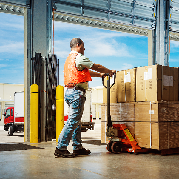 warehouse employee using a pallet jack to move boxes along the dock. 
