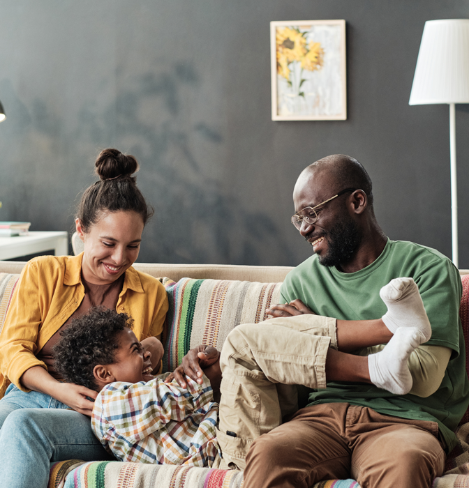 family playing on the couch with home security system watching their home.